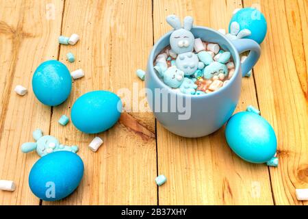 Osterkinder heiße süße Schokolade oder Kakao mit lustigen Marshmallow Hasen und ostereiern. Auf Holzhintergrund. Stockfoto