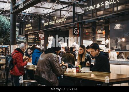 London, Großbritannien - 14. Dezember 2019: Menschen an den Tischen im Spitalfields Market, einer der besten viktorianischen Markthallen in London mit Ständen offeri Stockfoto