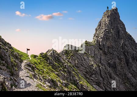 Ein einziger Kletterer auf einem Berggipfel und der Steile Weg zum Gipfel Stockfoto