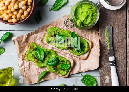 Zwei Kräcker mit grünem Spinathumus auf Holztisch. Flaches Lay. Hummus-Konzept. Lebensmittelfotografie Stockfoto