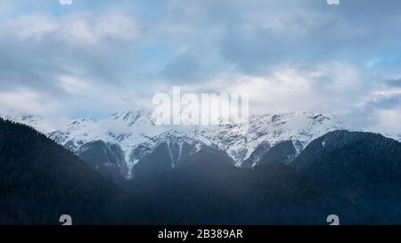 Wintersee Ritsa in Abchasien mit Bergen im Schnee im Hintergrund, am späten Abend. Dramatisches Wetter in kalten Blautönen. Stockfoto