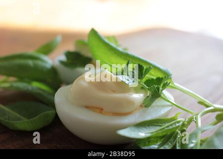 Gekochte Eier mit frischem Baby-Blattspinat und Petersilie auf der Holzschnittplatte. Schnelles und einfaches Frühstücksrezept im Frühjahr. Kopierbereich Stockfoto