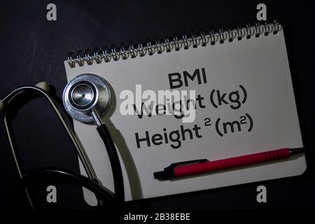 BMI - Gewicht und Höhe schreiben Sie auf ein Buch, das auf dem Office Desk isoliert ist. Gesundheitskonzept oder medizinisches Konzept Stockfoto