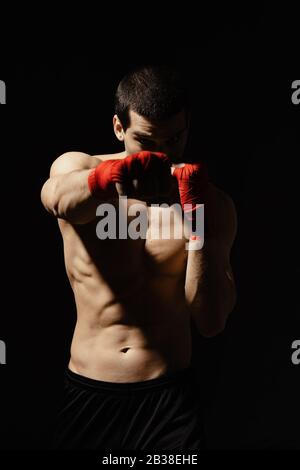 Sportboxer stanzen mit Entschlossenheit und Vorsorge über schwarzem Hintergrund. Konzept für Stärke, Angriff und Bewegung. kaukasisches Modell in Bewegung bringen Stockfoto