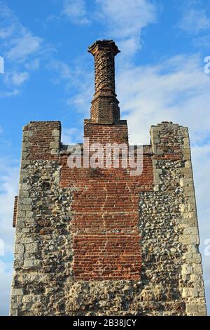 Tudor verdrehte Gersten-Zuckerschornstein-Topf auf mittelalterlichen Kaminstapeln mit verschiedenem Ziegelstein und Steinwerk und einem blauen Himmel mit weißem Wolkenhintergrund. Stockfoto