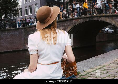 Frau in weißem Kleid mit Blick auf den Kanal und Menschenmengen Stockfoto