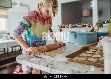 Mädchen Ausrollen Teig mit Weihnachtsbeleuchtung im Hintergrund Stockfoto