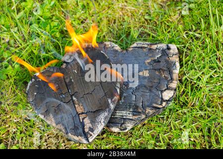 Heiße Kohlen und brennende Hölzer in Form des menschlichen Herzens. Glühende und flammende Holzkohle, leuchtend rotes Feuer und Asche. .Close-up, Draufsicht. Stockfoto