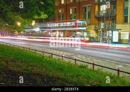 Eine lange Exposition eines roten Busses Nummer 18 auf der Harrow Road in kensal Green, Nord-West London. Stockfoto