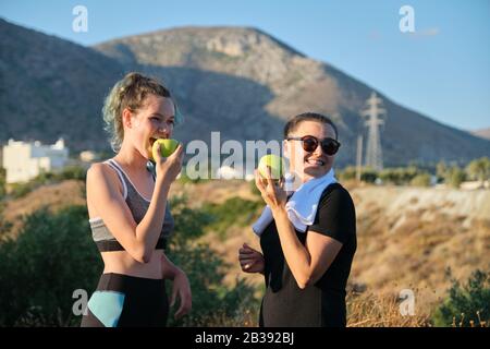 Zwei Frauen Mutter und Tochter im Teenageralter essen grüne Äpfel in der Natur Stockfoto