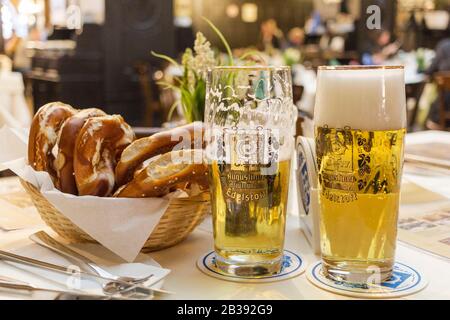 München, Deutschland - 8. Februar 2019 : Klassisches deutsches Abendessen mit gebratenen Würstchen mit geschmortem Kohl auf großen weißen Tellern mit hellem Bier, auf dem man steht Stockfoto