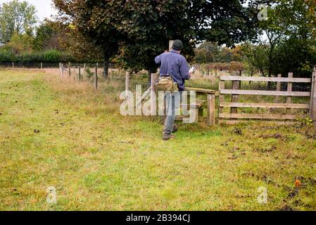 Walker überquert einen Zaun auf einem öffentlichen Pfad in Bibury, England in den Cotswolds. Stockfoto