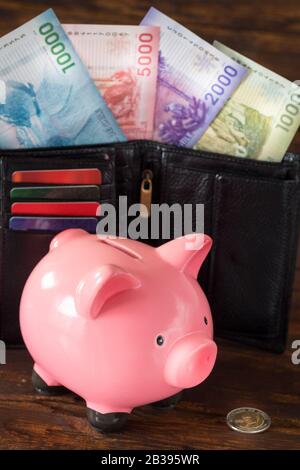 Schweinebank und Chile-Geld in der Brieftasche auf der Holztischplatte. Stockfoto