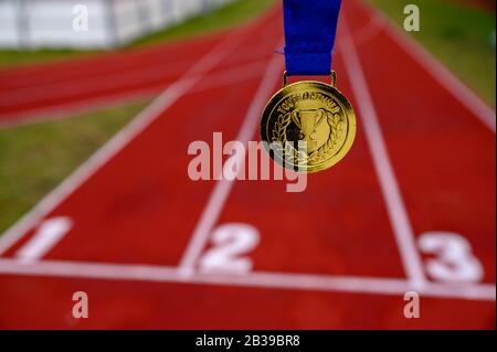 Du bist ein Gewinner, geschrieben auf der Goldmedaille, Leichtathletik Laufstrecke im Hintergrund Stockfoto