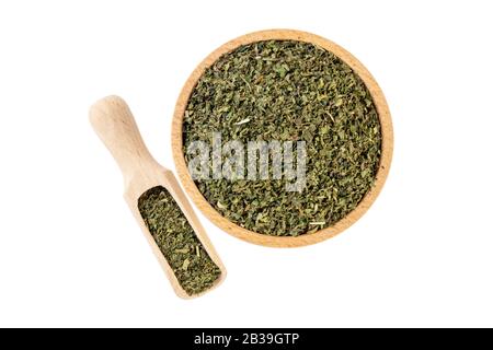 Getrocknetes Nesselkraut oder in lateinischem Utricae folium in Holzschale und Schaufel isoliert auf weißem Grund. Heilkräuter. Kräutermedizin. Alternat Stockfoto