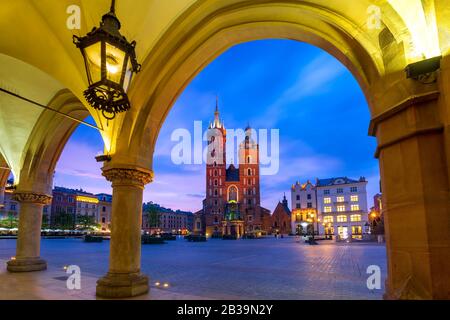 Die Basilika der Heiligen Maria auf dem mittelalterlichen Hauptmarktplatz, wie sie von Krakauer Tuchhalterei bei Sonnenuntergang, in Krakow, Polen, zu sehen ist Stockfoto