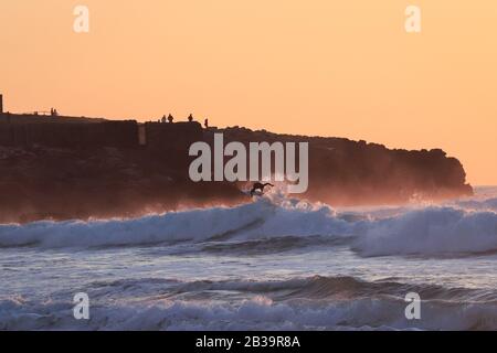 Surfer reitet während des Sonnenuntergangs auf einer Welle Stockfoto