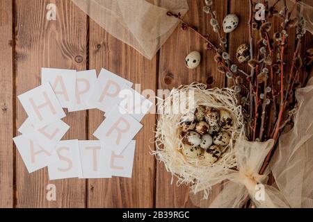 Flache Laienzusammensetzung aus Wachteleiern und Karte mit Text Happy Easter auf Holztisch. Draufsicht. Stockfoto