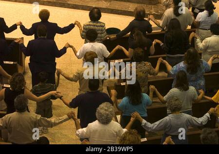 San Juan Texas USA, um 2004: Gemeindemitglieder halten während eines katholischen Gottesdienstes in der Basilika unserer Lieben Frau von Del Valle die Hände im Gebet fest. ©Bob Daemmrich Stockfoto