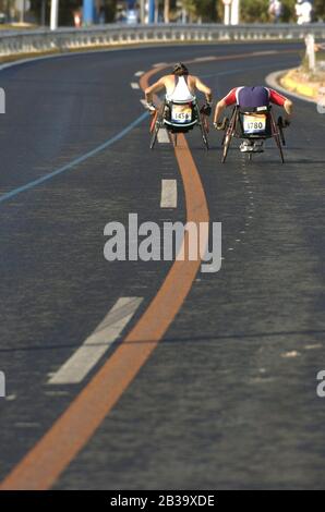 Athen, Griechenland 26 SEP 2004: Rollstuhlmarathonläufer gehen beim Paralympics-Marathon auf der traditionellen Marathon-Athen-Strecke einen Hügel hinauf. ©Bob Daemmrich Stockfoto