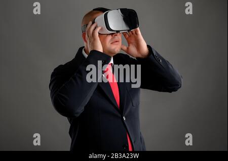 Geschäftsmann mit schwarzem Anzug und Virtual Reality VR-Brille Stockfoto