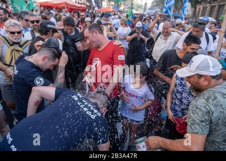 Buenos Aires, Argentinien; 10. Dezember 2019: Feuerwehrleute, die an einem heißen Tag Wasser während Mobilisierungen zur Unterstützung und Feier für die Annahme geben Stockfoto