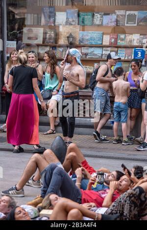 Buenos Aires, Argentinien; 10. Dezember 2019: Menschen, die auf dem Boden ruhen und eine Person, die während des Mo mit einer Maske des präsidenten in Annahme geht Stockfoto