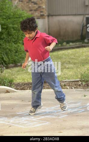 Austin, Texas USA, 12. FEB 2001: SPIELENDE KINDER: Der 7-jährige hispanische Junge spielt in seiner Auffahrt einen Hoffnungsträger. ©Bob Daemmrich Stockfoto