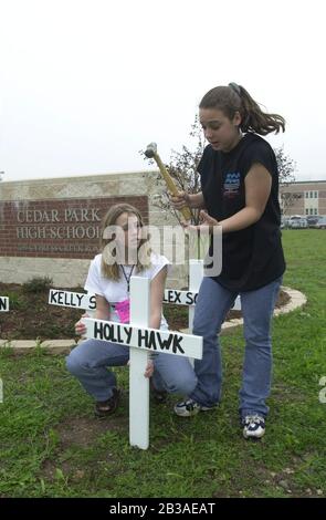 Cedar Park, Texas, 07. MÄRZ 2001: In der Cedar Park High School wurde eine von Studenten geführte Produktion von „Shattered Dreams“ mit dem simulierten Drama eines Teenagerunfalls, bei dem es sich um einen Verkehrsunfall handelt, der mit Polizisten, Krankenwagen, einem medizinischen Evakuierungshubschrauber und einem Leichenwagen durchgeführt wurde, inszeniert, um den Schülern zu helfen, während der Frühjahrssaison nicht zu trinken und zu fahren. An der Produktion nahmen Dutzende von Studenten als Unfallopfer, Berater und weinende Verwandte Teil, darunter eine Beerdigungs-Produktion mit Schatullen und trauernden Eltern. Hier stellen zwei Schüler vor der Schule ein Gedenkkreuz auf. ©Bob Daemmrich Stockfoto