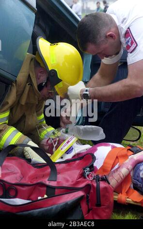 Cedar Park, Texas 07 MAR 2001: Eine von Studenten geführte Produktion von „Shattered Dreams“ mit dem simulierten Drama eines Teenagerunfalls, der im Rausch war (DUI), komplett mit Polizisten, Krankenwagen, medizinischem Evakuierungshubschrauber und einem Leichenwagen, wurde an der Cedar Park High School inszeniert, um Schülern zu helfen, nicht zu trinken und zu fahren. An der Produktion nahmen Dutzende von Studenten als Unfallopfer, Berater und weinende Verwandte Teil, darunter eine Beerdigungs-Produktion mit Schatullen und trauernden Eltern. Hier entfernen Ersthelfer ein „Opfer“ aus einem umgedrehten Auto, während die Studenten das Drama beobachten. ©Bob Daemmrich Stockfoto