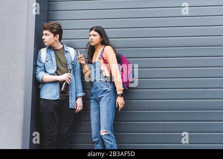 Junge und brünette Teenager rauchen Zigarette und trinken Bier Stockfoto