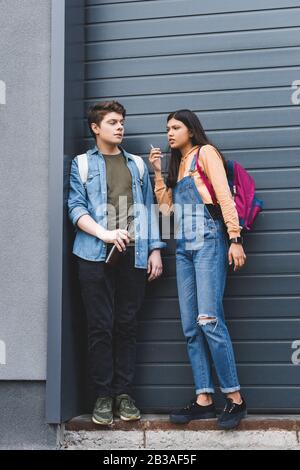 Junge und ziemlich brünette Teenager, die Zigarette rauchen und Bier trinken Stockfoto