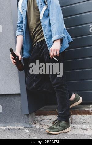 3/4-Ansicht des Jungen, der Zigarette raucht und Bier trinkt Stockfoto