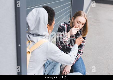 afroamerikanischer Junge, der eine Zigarette blonder und hübscher Teenager zündet Stockfoto