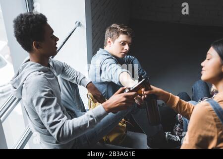 Fröhliche und lächelnde Teenager, die auf Treppen sitzen und klinken Stockfoto
