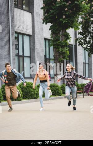 Verspielte und fröhliche Teenager, die mit Skateboard laufen und lächeln Stockfoto