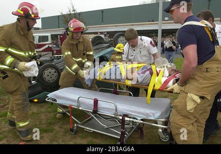 Cedar Park, Texas 07 MAR 2001: Eine von Studenten geführte Produktion von „Shattered Dreams“ mit dem simulierten Drama eines Teenagerunfalls, der im Rausch war (DUI), komplett mit Polizisten, Krankenwagen, medizinischem Evakuierungshubschrauber und einem Leichenwagen, wurde an der Cedar Park High School inszeniert, um Schülern zu helfen, nicht zu trinken und zu fahren. An der Produktion nahmen Dutzende von Studenten als Unfallopfer, Berater und weinende Verwandte Teil, darunter eine Beerdigungs-Produktion mit Schatullen und trauernden Eltern. Hier legen Ersthelfer Unfallopfer auf die Liege. ©Bob Daemmrich Stockfoto