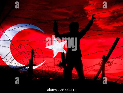 Slhouette der Frau, die durch den Stacheldrahtzaun blickt und die türkische Flagge überlagert. Asyl, Flüchtlinge, Türkei/Griechenland Anspannung..., Konzept Stockfoto