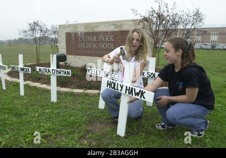 Cedar Park, Texas, 07. MÄRZ 2001: In der Cedar Park High School wurde eine von Studenten geführte Produktion von „Shattered Dreams“ mit dem simulierten Drama eines Teenagerunfalls, bei dem es sich um einen Verkehrsunfall handelt, der mit Polizisten, Krankenwagen, einem medizinischen Evakuierungshubschrauber und einem Leichenwagen durchgeführt wurde, inszeniert, um den Schülern zu helfen, während der Frühjahrssaison nicht zu trinken und zu fahren. An der Produktion nahmen Dutzende von Studenten als Unfallopfer, Berater und weinende Verwandte Teil, darunter eine Beerdigungs-Produktion mit Schatullen und trauernden Eltern. Hier stellen zwei Schüler vor der Schule ein Gedenkkreuz auf. ©Bob Daemmrich Stockfoto