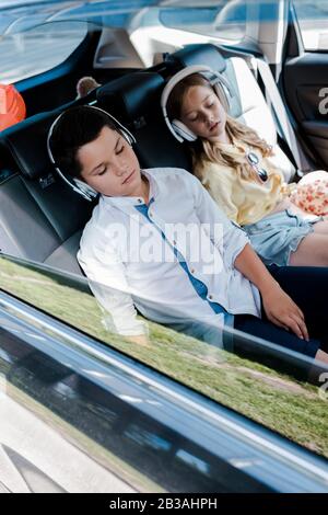 Selektive Fokussierung süßer Kinder in Kopfhörern, die im Auto schlafen Stockfoto