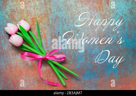 Blumenstrauß aus drei rosafarbenen Tulpenblumen aus Holz auf strukturiertem Hintergrund. Text Happy Frauentag Grußkarte Poster Banner. Frühling International h Stockfoto