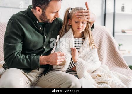 Aufmerksamer Vater, der die Stirn der erkrankten Tochter berührt Stockfoto