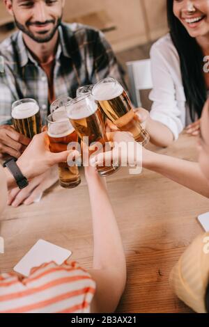 Teilweise Blick auf multikulturelle Freunde, die in der Kneipe eine Brille von leichtem Bier einklinken Stockfoto