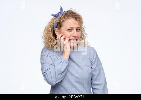 Junges nervöse Mädchen, die ihre Nägel beißt, besorgt, Fehler gemacht zu haben. Studio gedreht. Negative menschliche Emotionen im Gesicht. Stockfoto