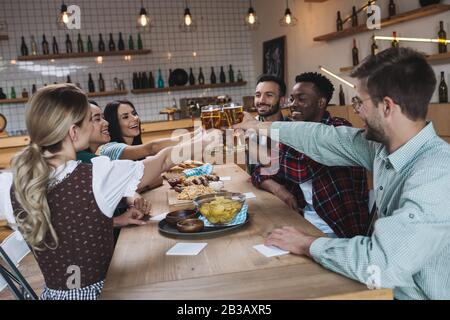 Fröhliche multikulturelle Freunde klinken Gläser helles Bier und feiern oktoberfest in der Kneipe Stockfoto