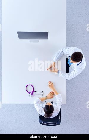 Draufsicht, flacher Lay. Die Ärzte in einem Büro im Krankenhaus diskutieren, während sie mit einem Stethoskop an einem Tisch sitzen Stockfoto