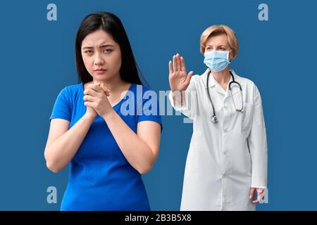 Kranke und junge Erwachsene asiatische Frau, die vor einem mittleren Alter steht Stockfoto