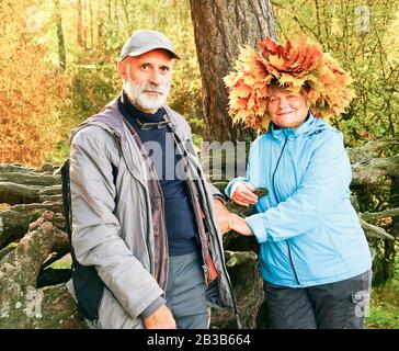 Eine Frau mit einem Kranz aus gelbem Ahorn hinterlässt auf dem Kopf neben einem Mann Stockfoto