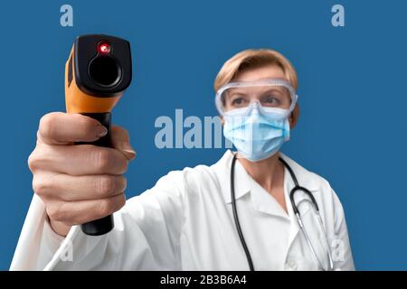 Arzt im mittleren Alter, der Infrarot-Thermometer in der Hand hält Stockfoto