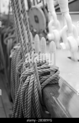 Seile, die an verspätet eingebackene Stifte gebunden sind, sind im Januar 2013 im norwegischen Tallship Christian Radich in Philipsburg, Sint Maarten, eingedockt. Flacher Freiheitsgrad. BW. Stockfoto